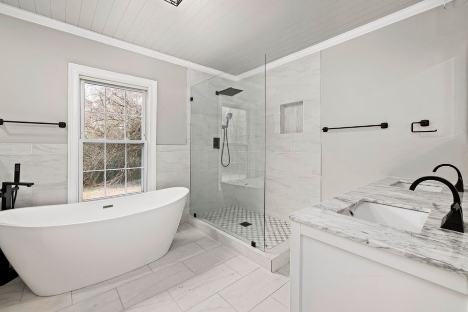 Sleek bathroom featuring a freestanding tub, glass shower, and marble accents.